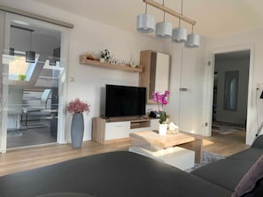 A modern living room with a flat-screen TV, wooden coffee table, and a sofa.