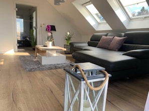 A modern living room with a black sofa, a white coffee table, and a glass-top table with a rope handle.