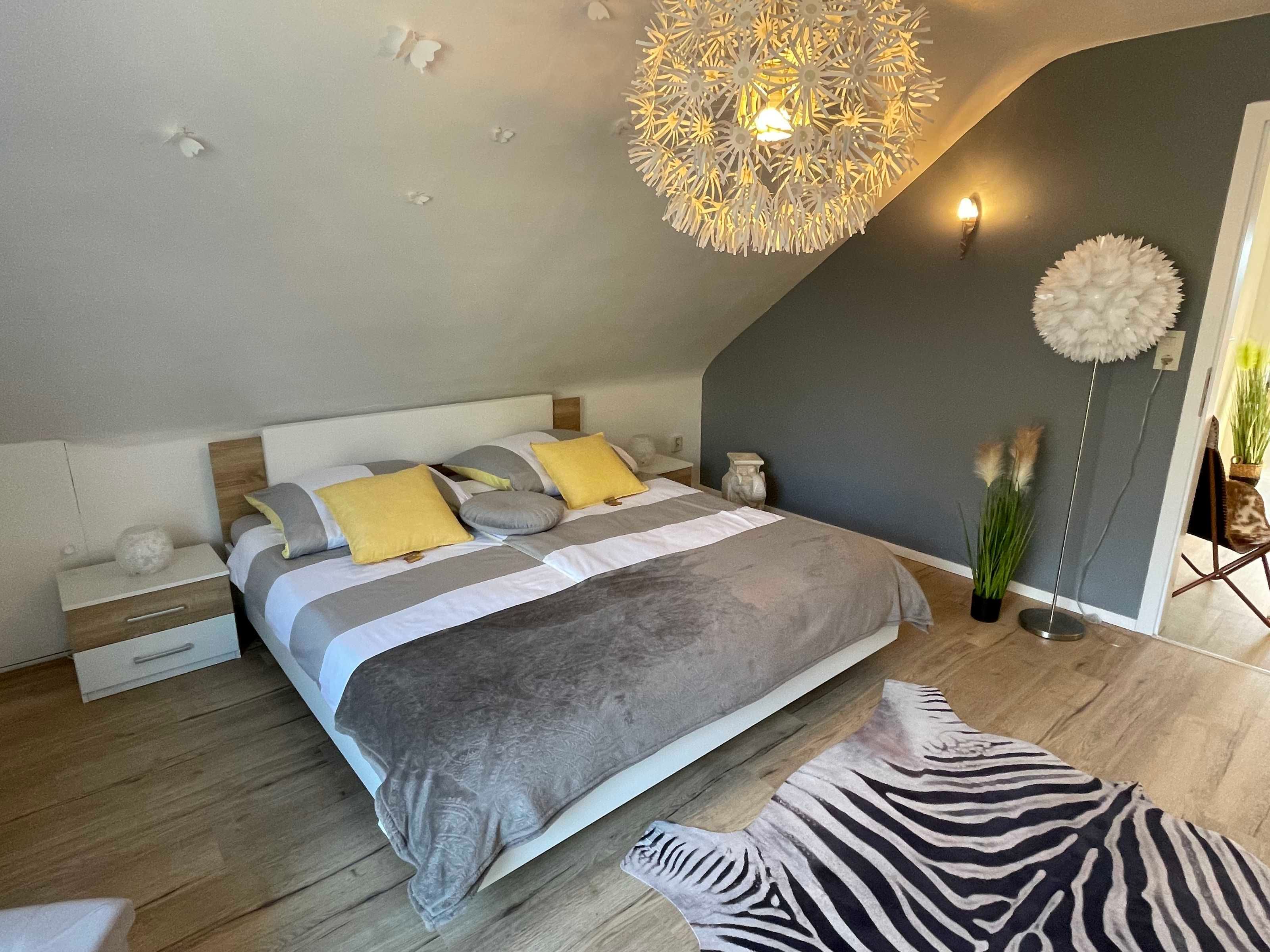 A bedroom with a bed, bedside tables, a floor lamp, and a zebra-patterned rug.