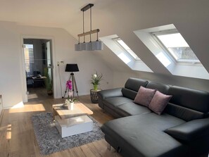 Ein modernes Wohnzimmer mit einer schwarzen Ledersofa, einem weißen Couchtisch und einem Oberlicht.