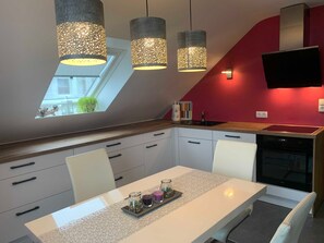 Eine moderne Küche mit Essbereich, Oberlicht und einem an der Wand befestigten Flachbildfernseher.