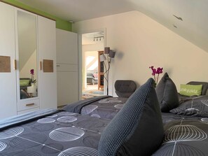 A bedroom with a bed, a wardrobe, a mirror, and a view into an adjacent room.