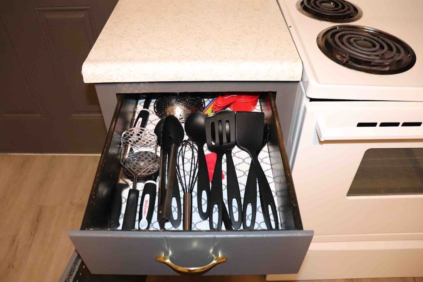 Un cajón de cocina con diferentes utensilios y un colador.