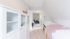 A bedroom with a bed, a wardrobe, and a hallway leading to a living area.
