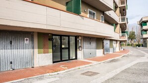 Ein mehrgeschossiges Gebäude mit geschlossenen Fensterläden, einem sichtbaren Eingang und einem Fußweg.