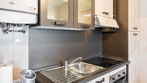 Eine Küche mit einer Edelstahl-Spüle, einem Backofen und einer Baxi-Gaskochstelle.