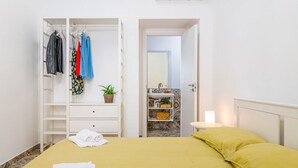 Una habitación con cama, armario, baño y mesita de noche con lámpara.