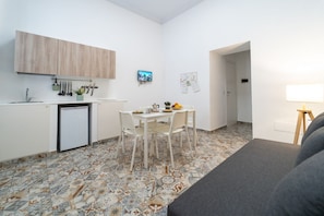 Un espace de vie compact comprenant un coin cuisine, un coin repas et un coin salon.
