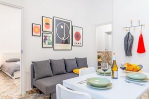 Ein modernes Wohnzimmer mit einer Couch, einem Esstisch und Kunstwerken an der Wand.