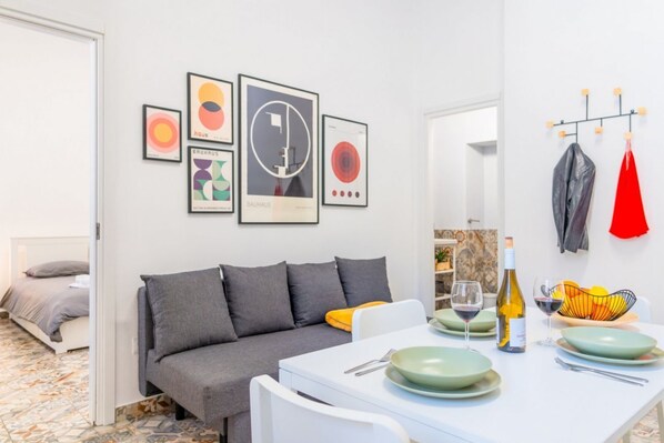 Una sala moderna con sofá, mesa de comedor y una obra de arte en la pared.