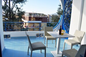 Ein Balkon mit Korbmöbeln, einem Tisch und einer Weinflasche.