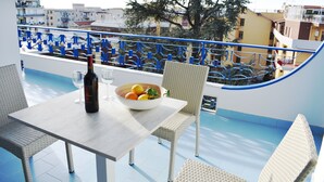 Ein Balkon mit Tisch, Stühlen, einer Flasche und einer Schale mit Obst.