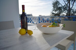 A table with a wine bottle, a glass, and a bowl containing lemons and a green plant. - Artistic Apartment in the Center of Sorrento (SORRENTO)