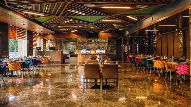 En rummelig hotellobby med barområde, polerede marmorgulve og moderne træloftdesign.