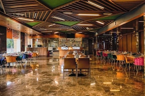 Un amplio vestíbulo de hotel con zona de bar, suelos de mármol pulido y moderno diseño de techo en madera.