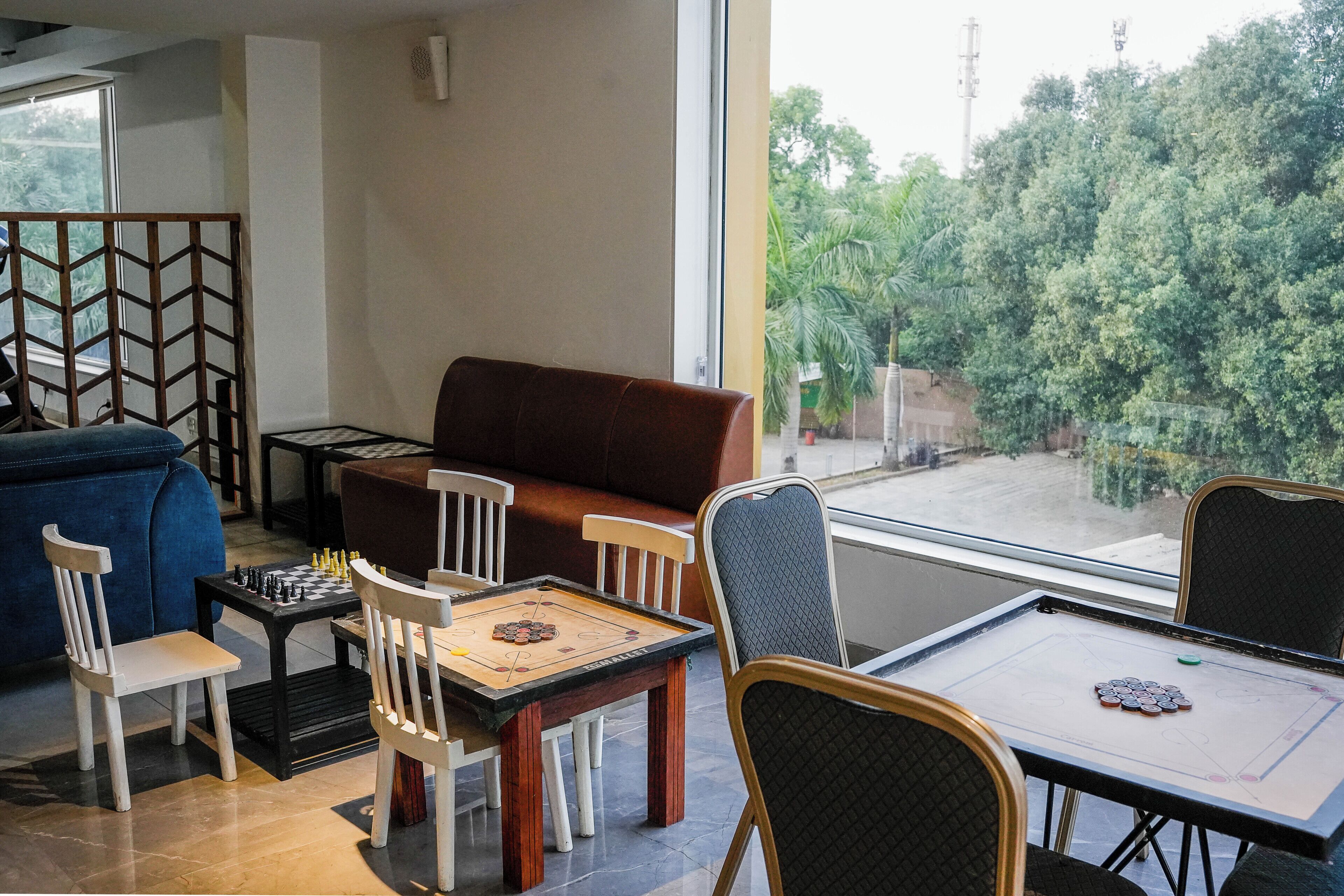 Une pièce avec un canapé, des fauteuils, une table sur laquelle est posé un jeu de société, et une vue par la fenêtre.