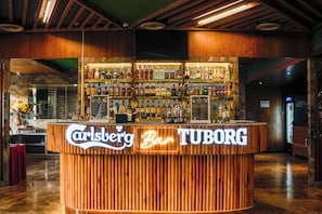 Un bar con mostrador de madera y un letrero que dice 'Carlsberg Bar TUBORG'.