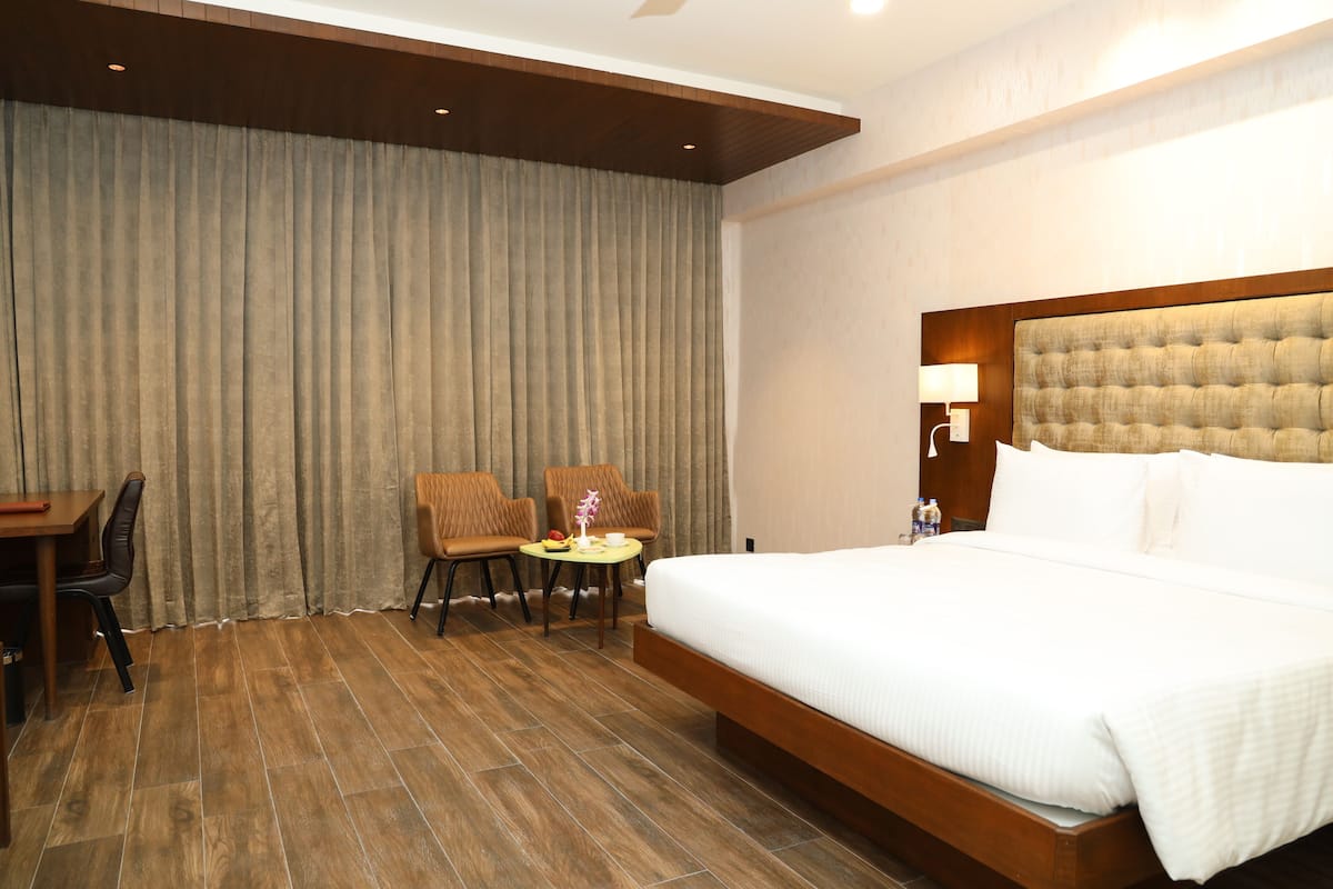 A hotel room with a large bed, a desk, two chairs, and a small table.
