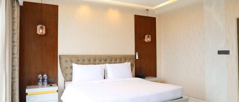 Una habitación de hotel moderna con una cama grande, mesitas de noche y una lámpara en el techo.