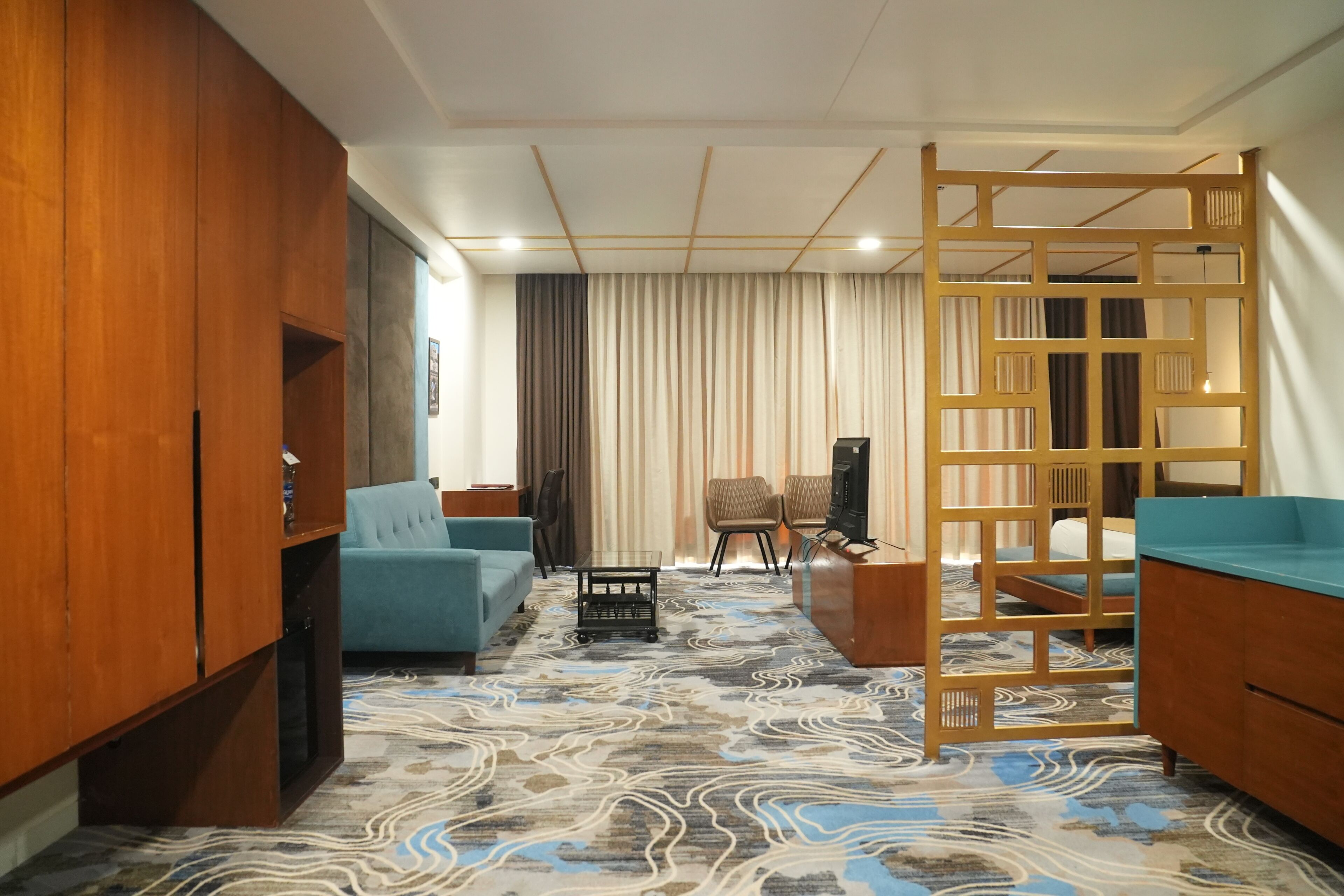 Ein Hotelzimmer mit einer Couch, einem kleinen Tisch, einer Holzwand und einem gemusterten Teppich.