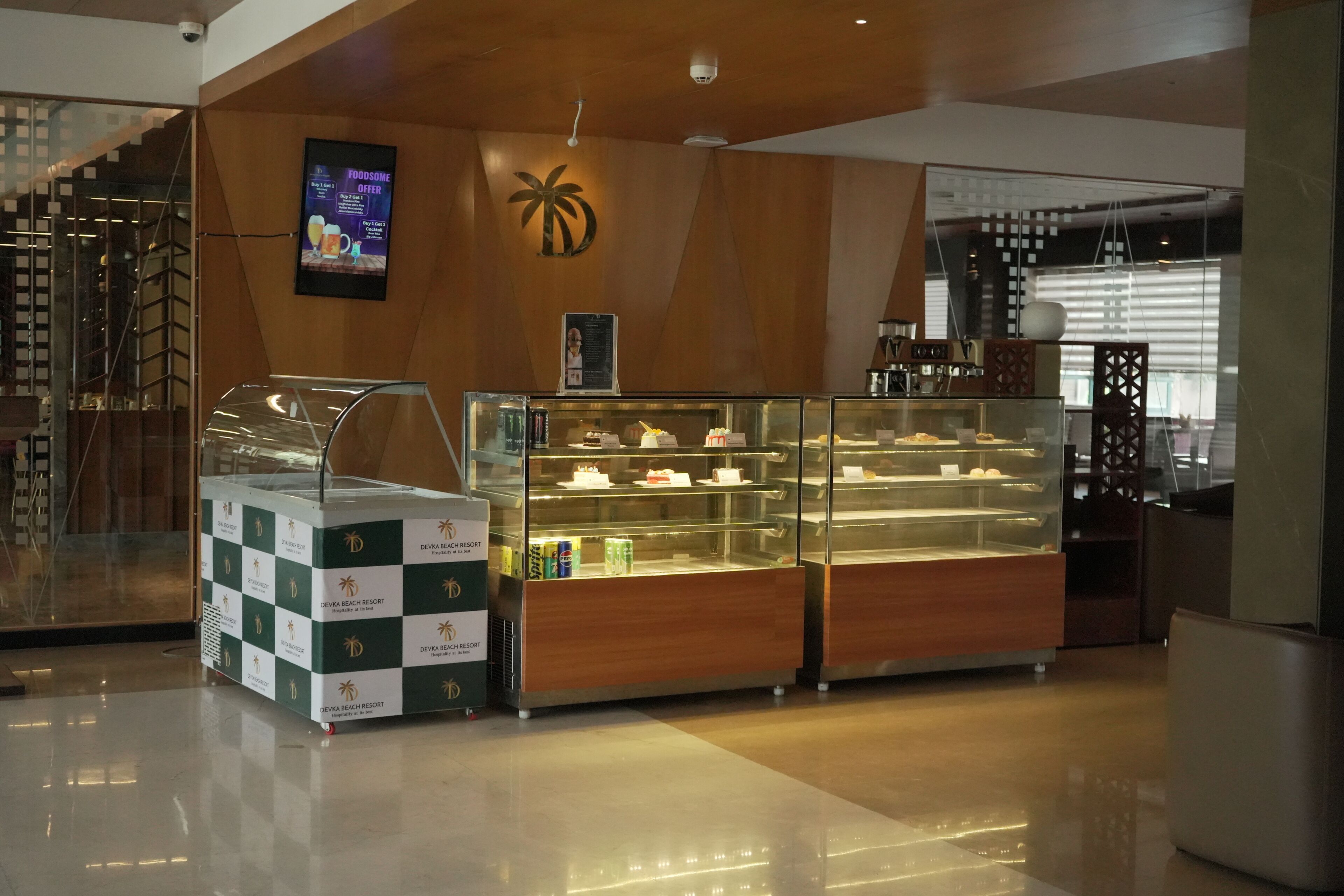 A dessert display case in a hotel lobby with a palm tree logo on the wall.