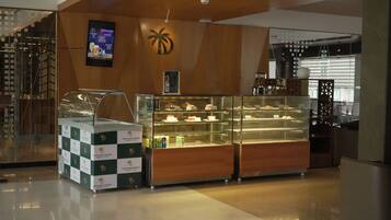 A dessert display case in a hotel lobby with a palm tree logo on the wall.