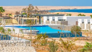 Un resort con piscina, vistas a la playa y edificios modernos.