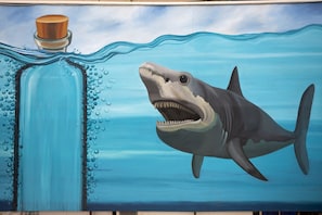 A mural of a shark swimming in water with bubbles and a bottle. - Koko Maya By Stone Wood (Morjim)