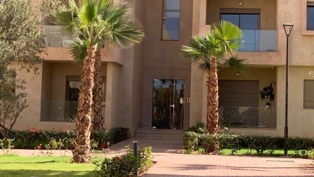 A multi-story building with a central entrance, surrounded by palm trees and a paved walkway. - La Perla de Marrakech (Marrakech)