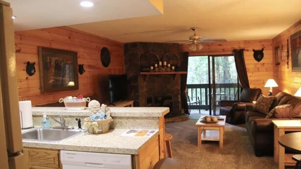A cozy cabin interior with a kitchen area, a fireplace, a seating area with a couch and chairs, and a dining table. - Hear the Waterfalls: Quiet Escape Near Downtown Gatlinburg (Gatlinburg)