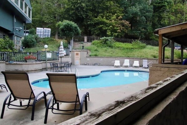Relax by the pool surrounded by lush greenery and a fence.
