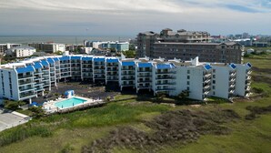 A multi-story hotel with a pool area, surrounded by greenery and a view of the ocean. - New listing!  Two bedroom, 2 bath with heated pool (Ocean City)