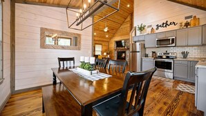 Un comedor amplio con una mesa y sillas de madera, una cocina con electrodomésticos modernos y una chimenea acogedora.