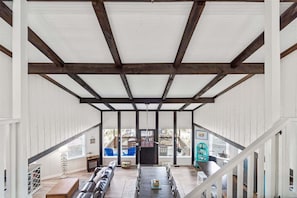 Un patio techado con mesa y sillas de madera, un sofá y una escalera que sube a un nivel superior.