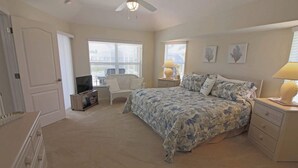 A bedroom with a bed, a TV, a chair, and a dresser.