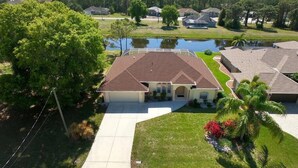 A residential area with a house featuring a large front yard, a driveway, and a small pond.