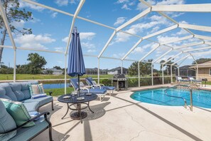 Un espacio al aire libre techado con piscina, sillas de descanso y una parrilla.