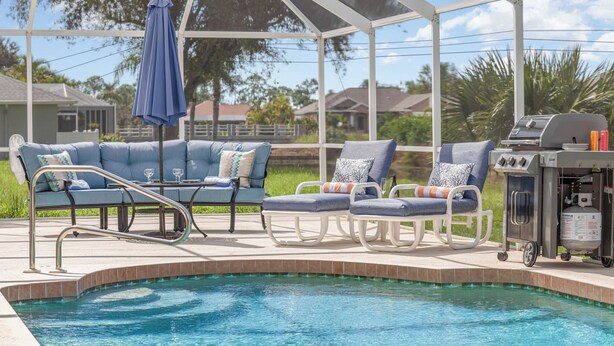 A poolside area with a covered seating area, a grill, and a pool.