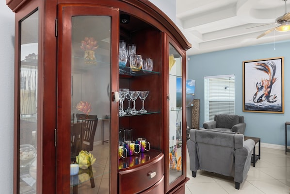 A living room with a wooden cabinet, a gray sofa, and a ceiling fan. - Sea Glass #10 | Coastal Condo • Community Pool • 3 Min Walk to Beach (South Padre Island)