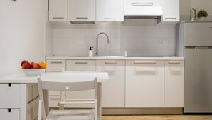 Een moderne keuken met witte kasten, een roestvrijstalen spoelbak en een koelkast.