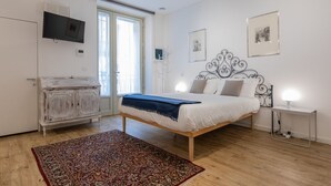 Een slaapkamer met een bed, een kledingkast, een televisie en een raam.