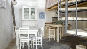 A compact kitchen with white cabinetry, a dining table with chairs, and a bunk bed structure.