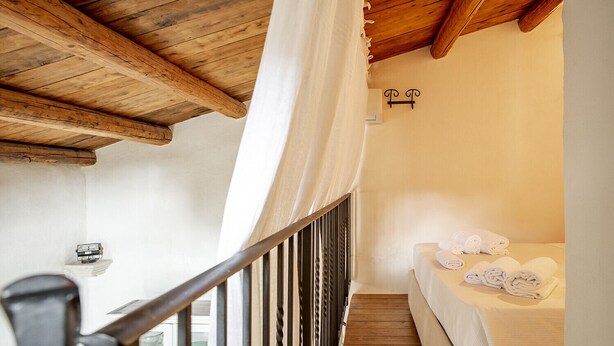 A staircase leading to a room with a bed, a small table, and a window with curtains.