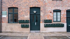A brick building with a green door, windows, and mailboxes. - Free Secure Parking | Stunning City Views (York)