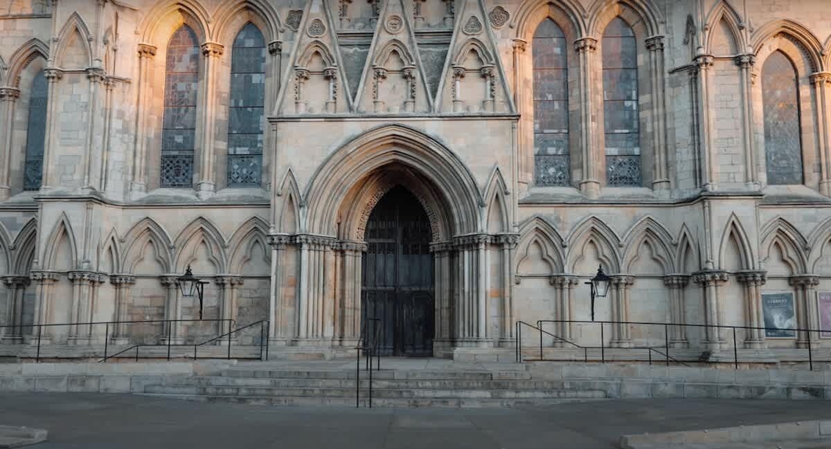 Un grand bâtiment historique, doté d’une entrée arquée imposante, de hautes fenêtres et de décorations en pierre complexes.