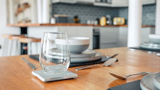 A dining table with a glass, cutlery, and plates in a modern kitchen setting. - Free Secure Parking | Stunning City Views (York)