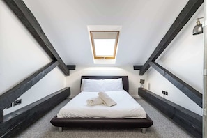 Un dormitorio con tragaluz, cama y mesita de noche.