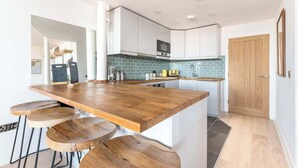 A modern kitchen with a wooden island, white cabinets, and a tiled backsplash. - Free Secure Parking | Stunning City Views (York)