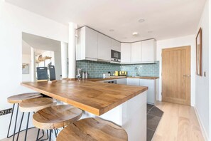 Una cocina moderna con una isla de madera, armarios blancos y un salpicadero de azulejos.