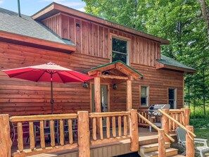 A wooden cabin with a porch, a red umbrella, and a grill outside. - Trails End House in Inlet (Inlet)